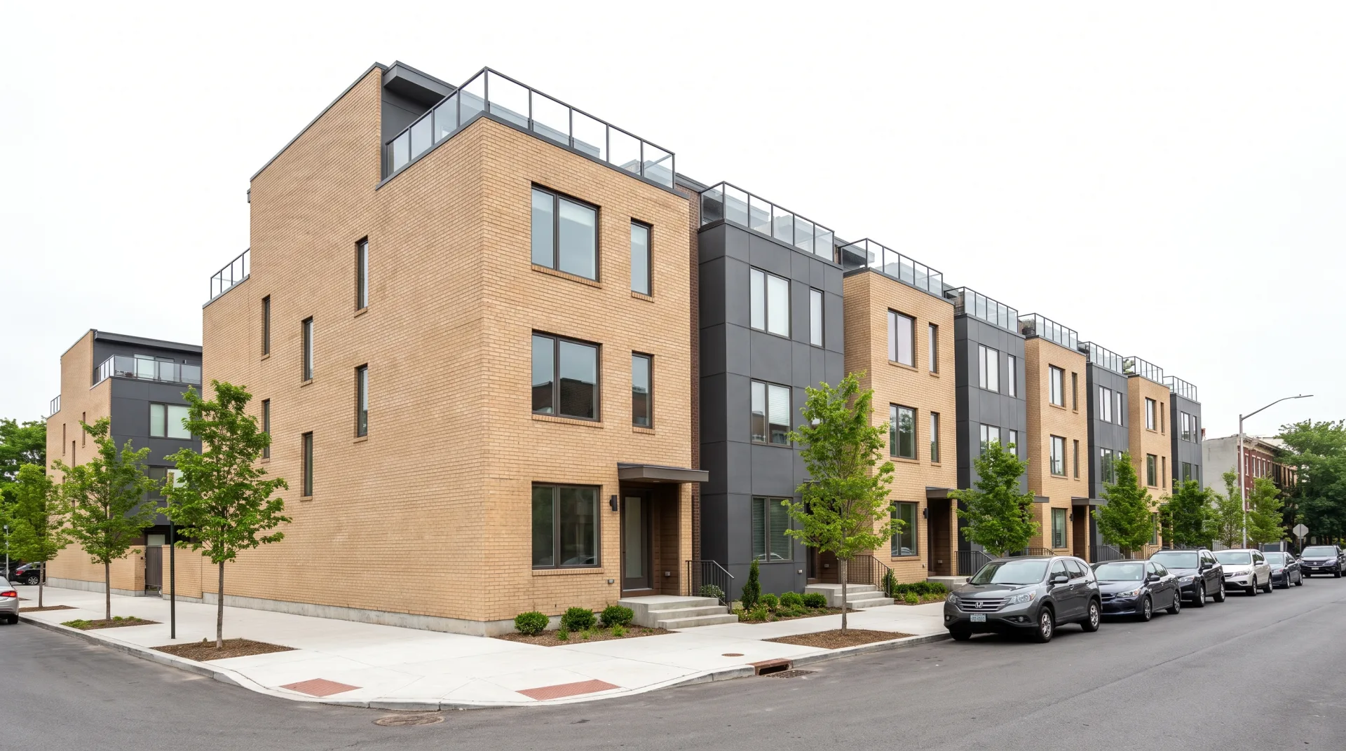 A row of six three-story townhouses in alternating buff brick and charcoal panels, seen along the sidewalk from the corner.